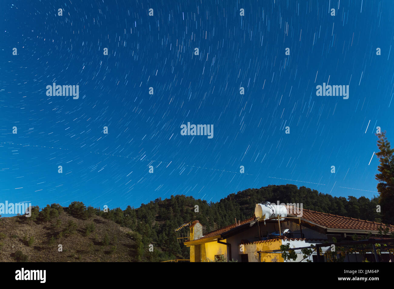 Tracce stellari nel corso di una casa presso i monti Troodos come un aereo attraversa il cielo. Acquisiti nel villaggio di Kakopetria in Cipro Foto Stock