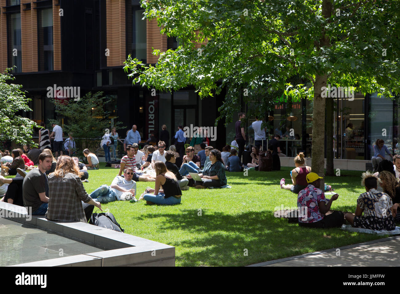 Dipendenti da uffici spillar fuori per il pranzo di erba a Battle Bridge Place, Kings Cross Foto Stock