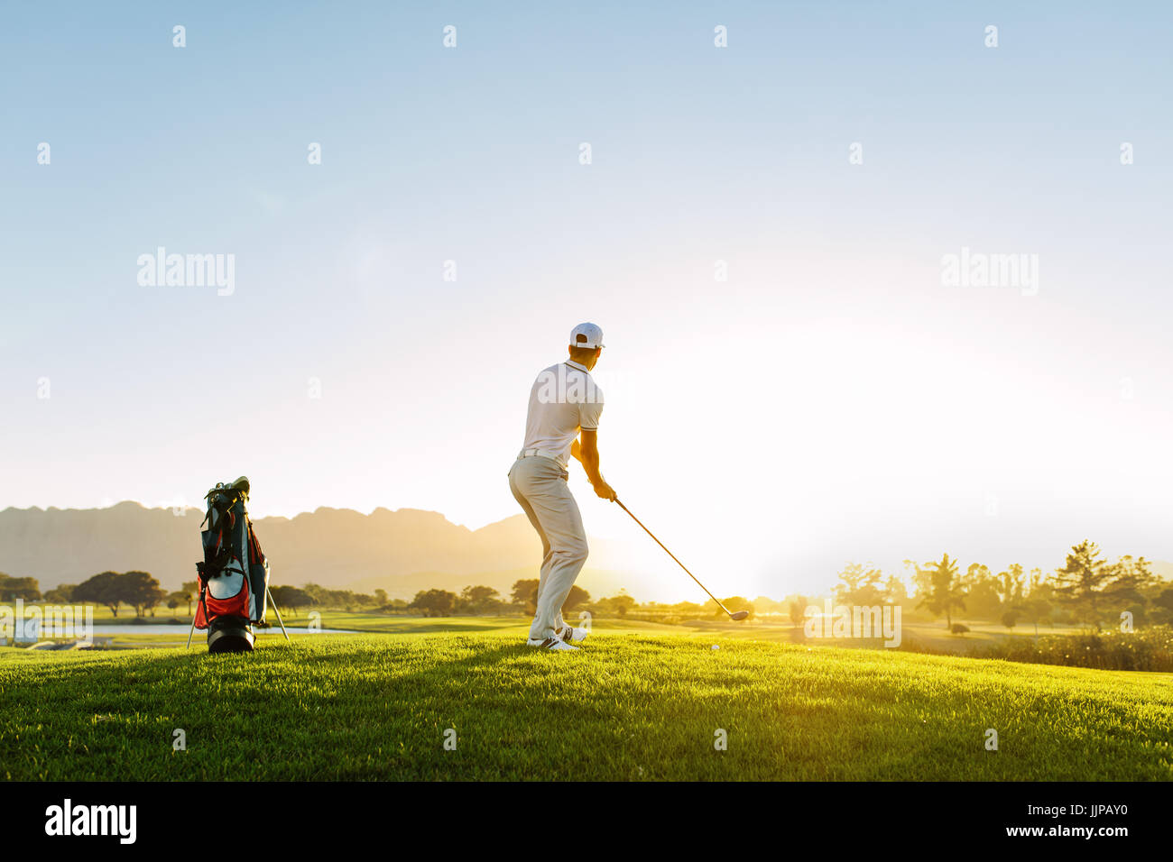 Per tutta la lunghezza del giocatore di golf per giocare a golf sul giorno di sole. Professional Golfer maschio tenendo girato sul campo da golf. Foto Stock