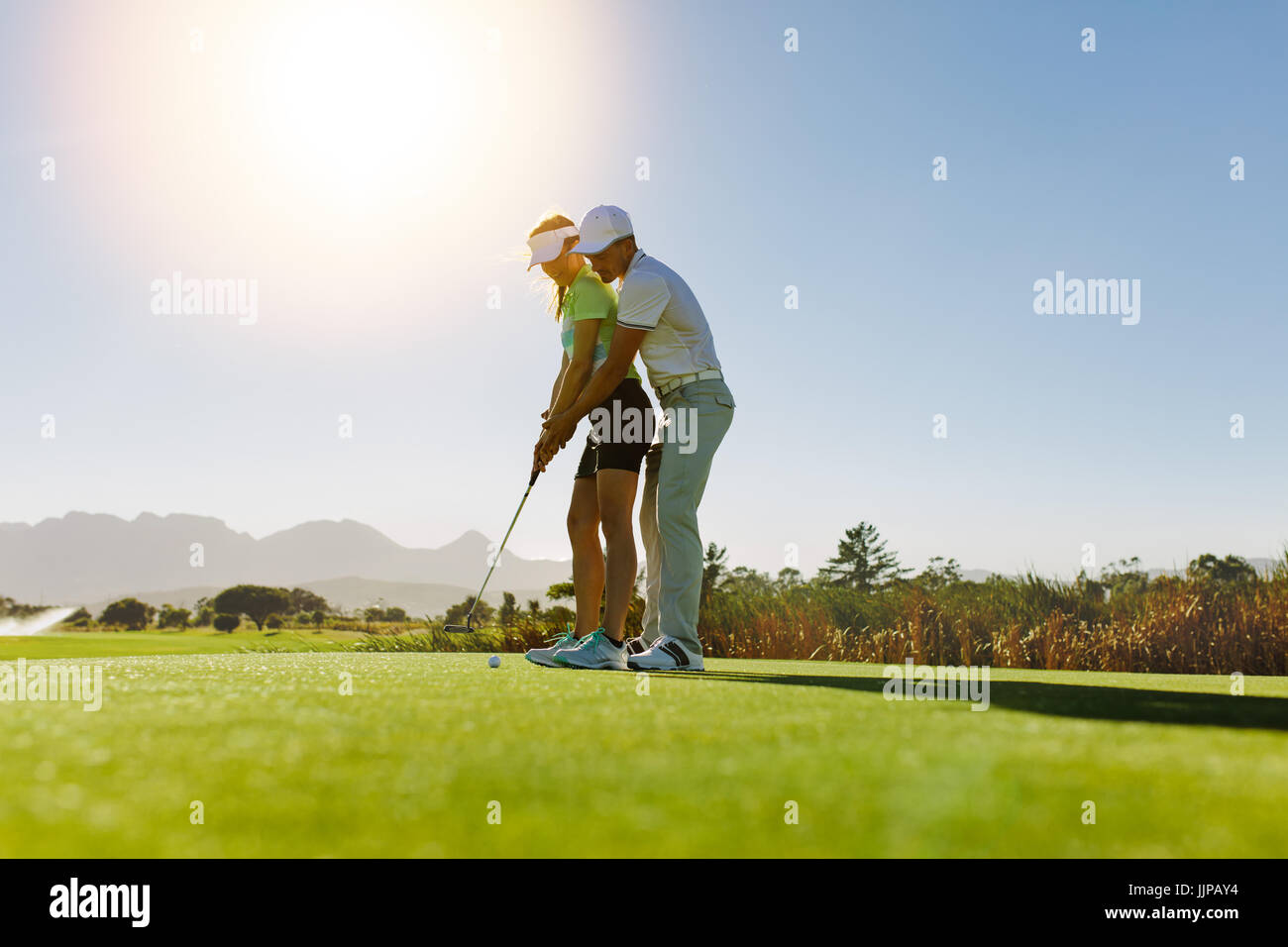 Uomo Donna di insegnamento per giocare a golf mentre si sta in piedi sul campo. Personal trainer dando lezione sul campo da golf. Foto Stock
