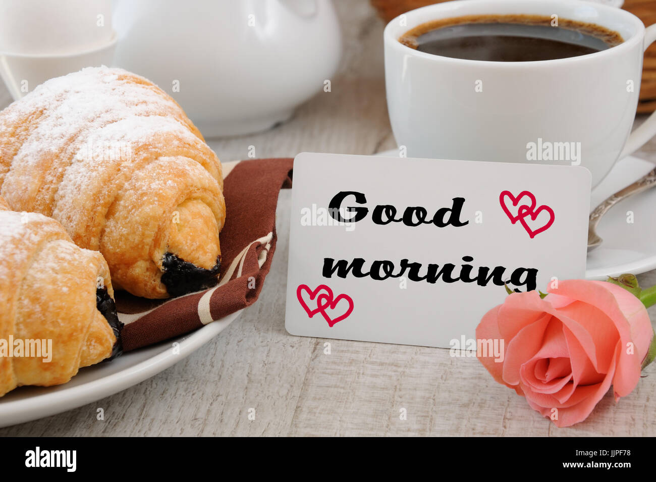 La prima colazione con croissant al cioccolato la coppa di riempimento di prodotti freschi caffè la mattina e una scheda con un augurio di buona mattina. Foto Stock