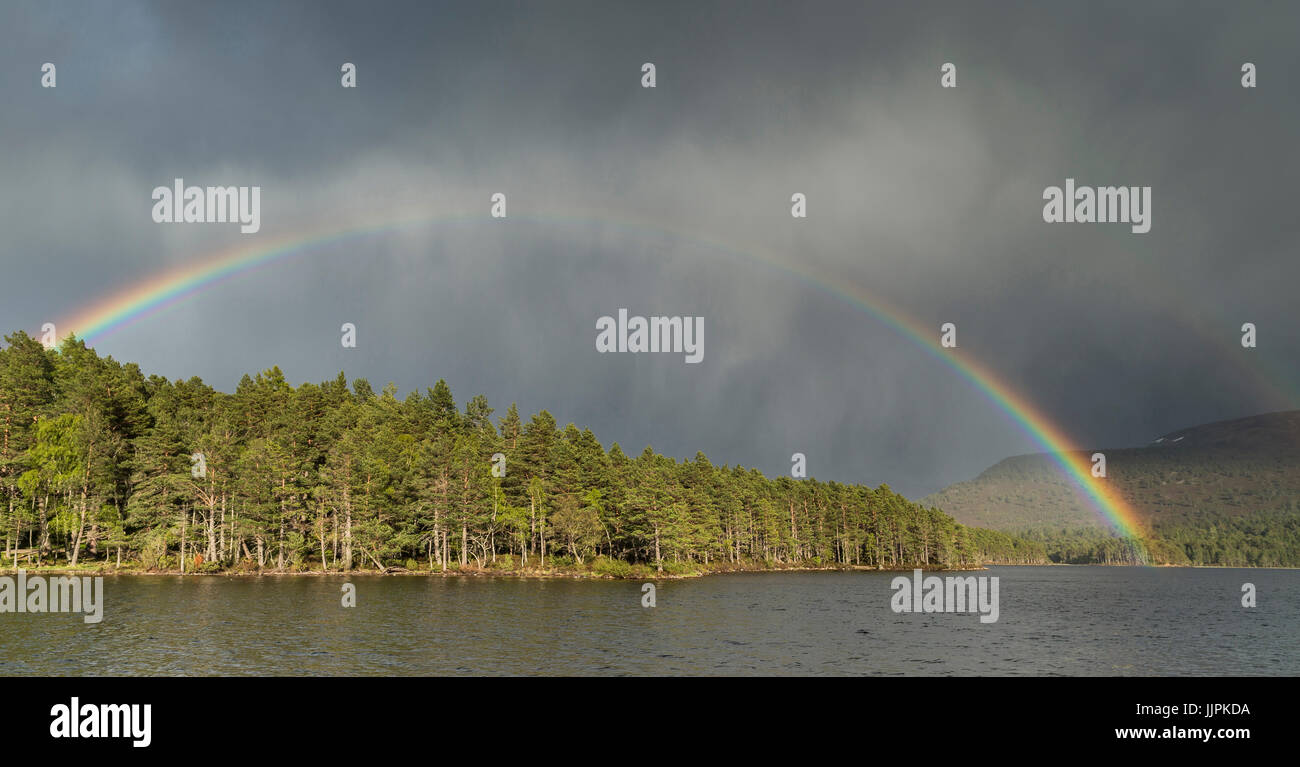 Rainbow e storm cloud sopra Loch un Eilein nei Cairngorms in Scozia. Foto Stock