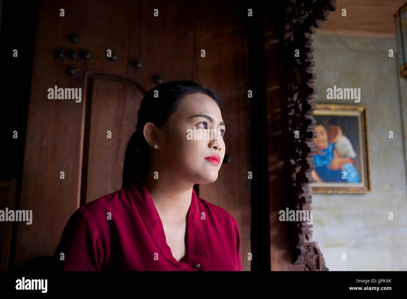 Giovane donna balinese di fronte a una porta di legno. Foto Stock
