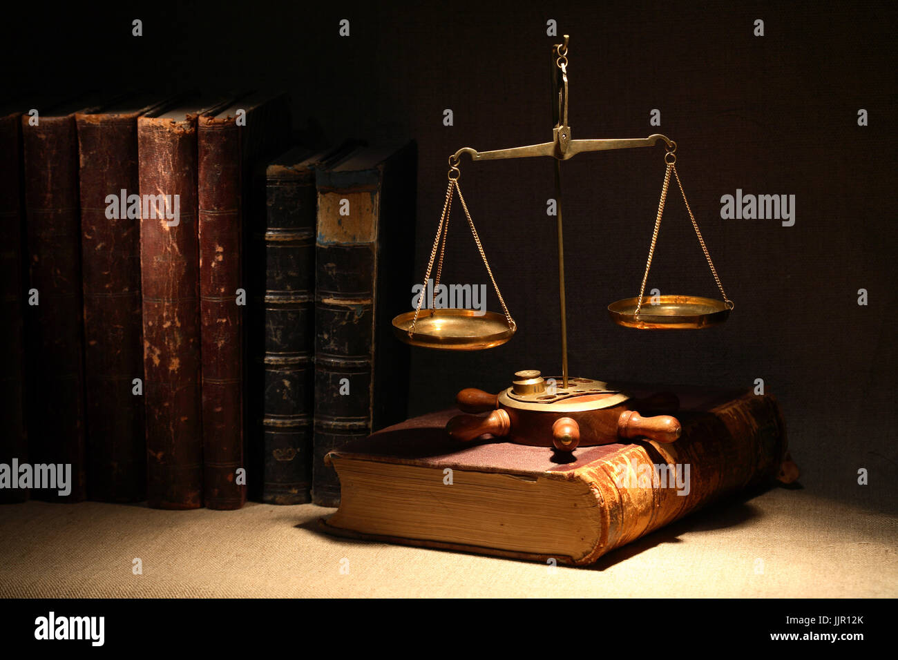 Concetto di legislazione. Ottone antico bilancia e libri antichi sotto il fascio di luce su uno sfondo scuro Foto Stock