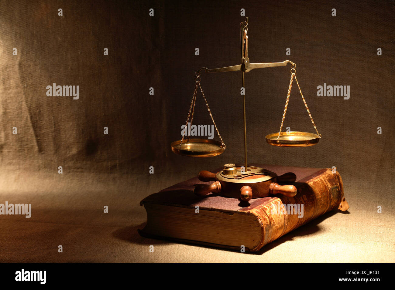 Concetto di legislazione. Ottone antico bilancia in piedi sul libro antico sotto il fascio di luce Foto Stock