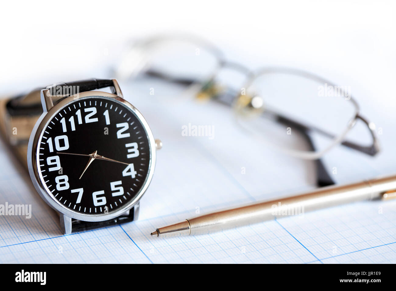 Extreme closeup di orologio da polso, penna e occhiali sul grafico sfondo della carta Foto Stock