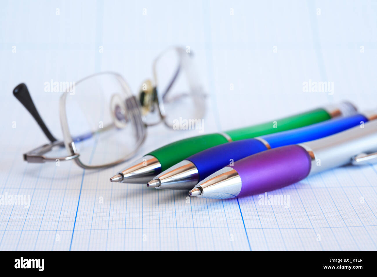 Extreme closeup di poco colore penna e occhiali sul grafico sfondo della carta Foto Stock