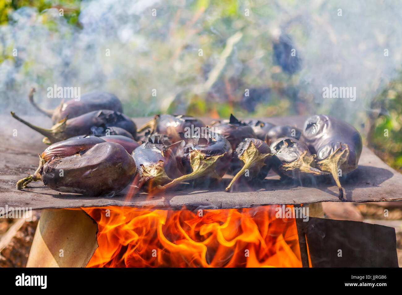Le melanzane cottura su una piastra di metallo su un fuoco aperto. Le melanzane cottura sull'arrosto naturale cibo. Foto Stock