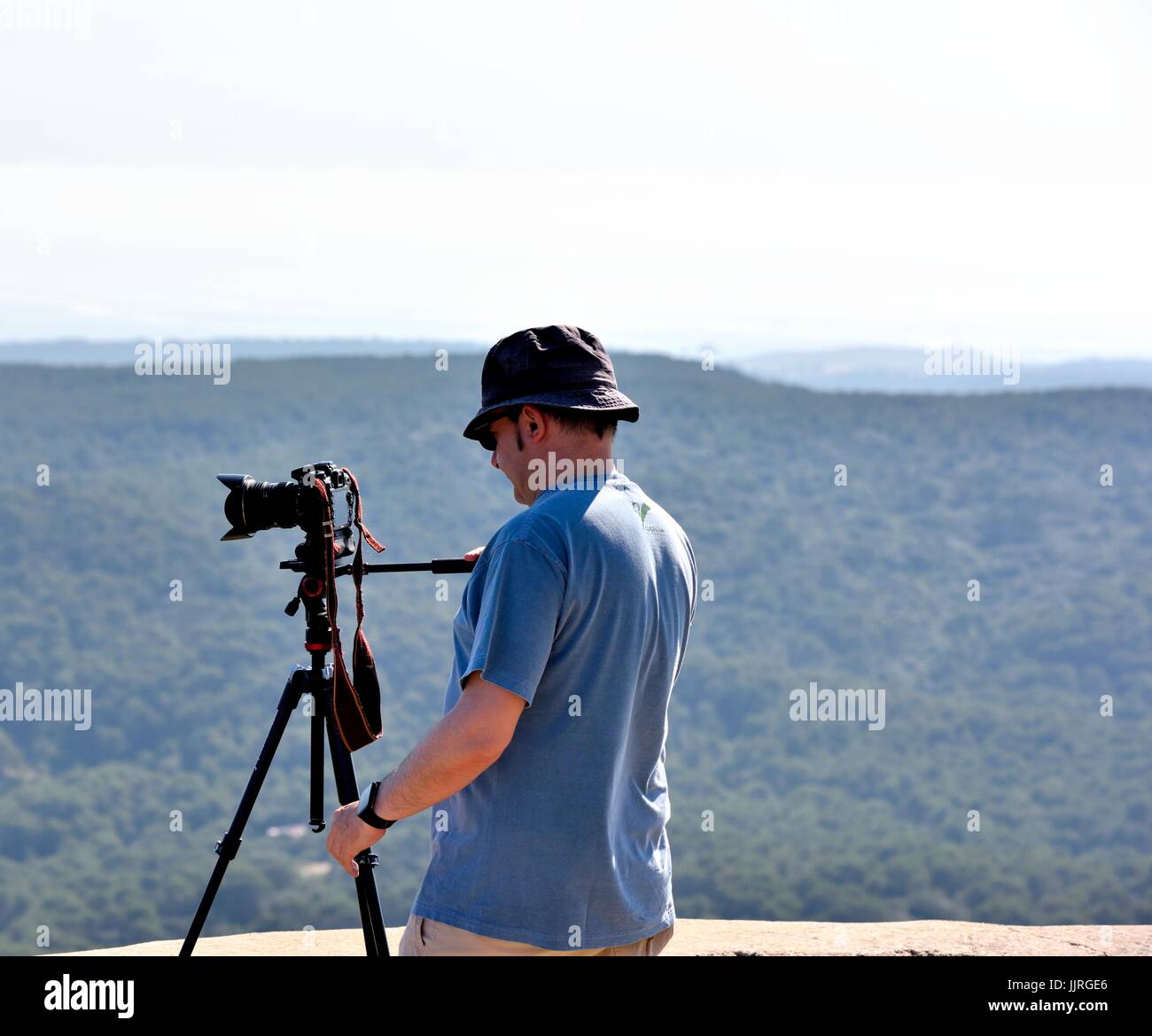 Uomo che utilizza SLR Fotocamera digitale su un treppiede Foto Stock