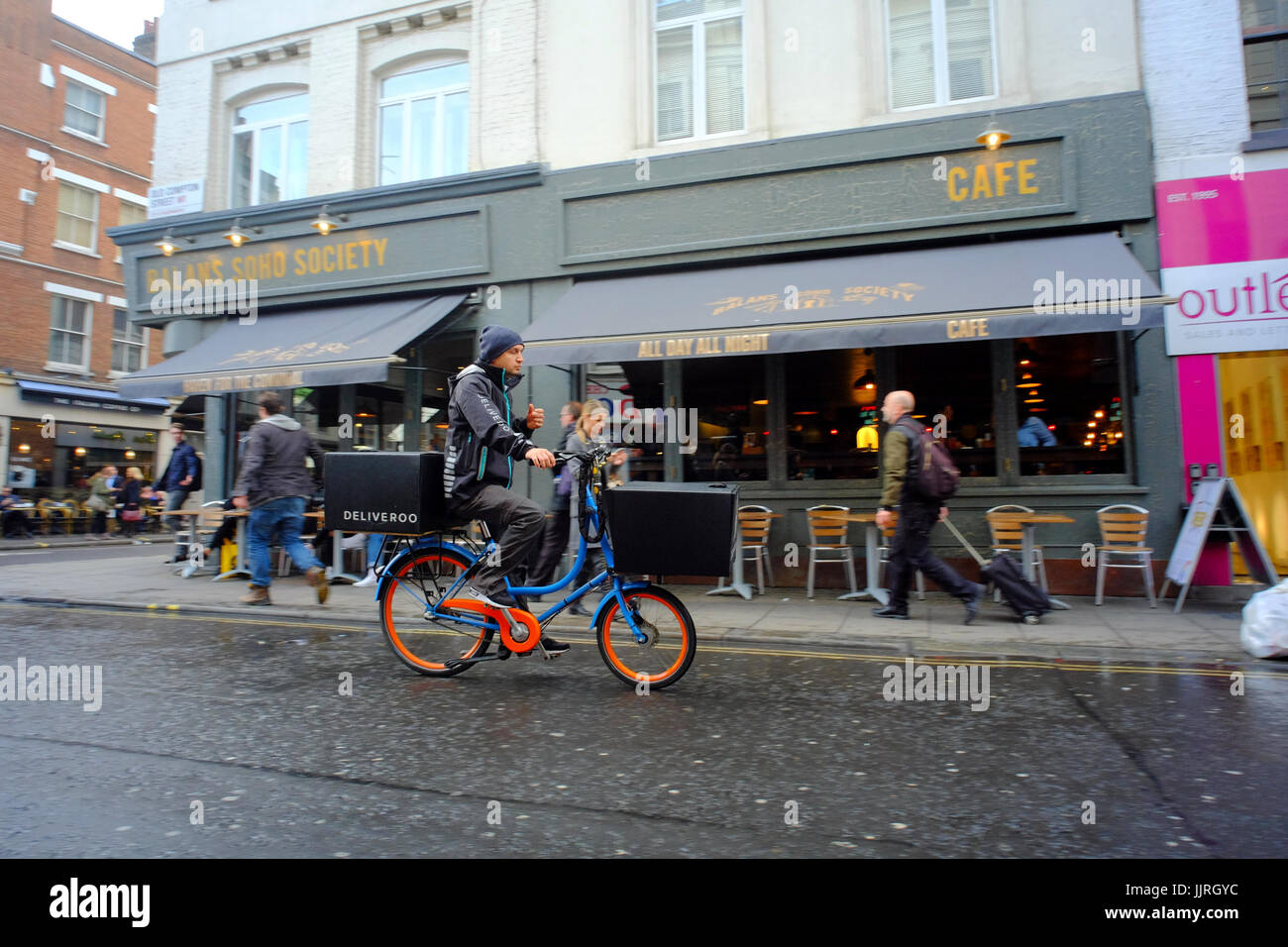Deliveroo Rider sotto la pioggia a Soho, London, Regno Unito Foto Stock