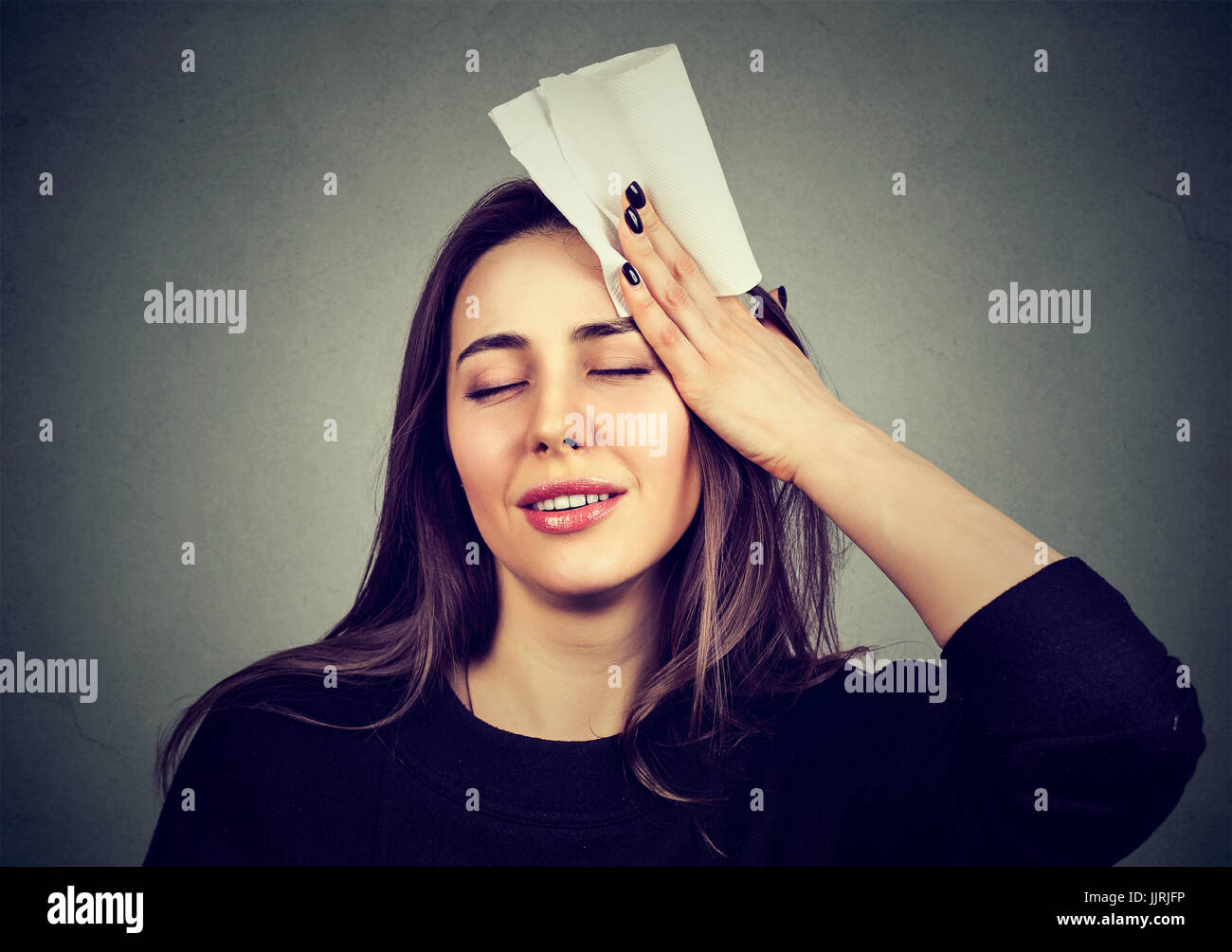 Giovane donna delle salviette sudore dalla sua fronte con un fazzoletto Foto Stock