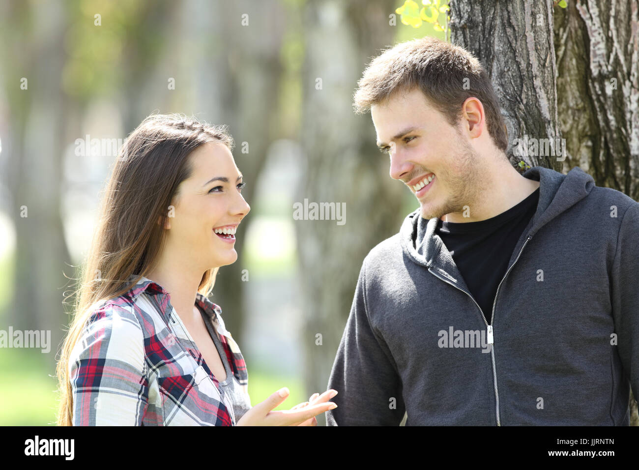 Due lieti teen amici parlando e guardando a vicenda in un parco Foto Stock
