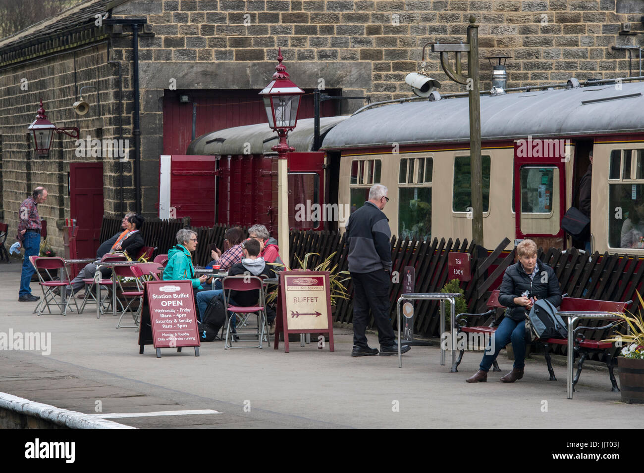 Le persone sulla piattaforma alla storica stazione Oxenhope, in un momento di relax a piccola caffetteria, chat & bere - Keighley e Worth Valley Railway Station, Inghilterra, Regno Unito. Foto Stock