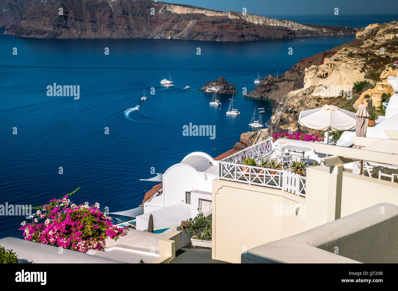 Villaggio di Oia - Santorini Cyclade islands, Grecia. Bellissima vista della città con edifici bianchi chiesa blu tetti e molti fiori colorati. Foto Stock