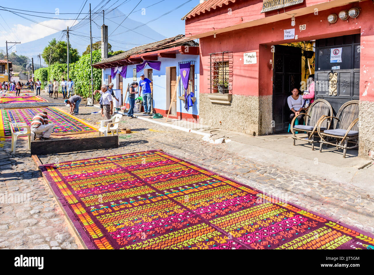 Antigua Guatemala - marzo 26, 2017: la gente fa segatura colorata processione tappeti durante la quaresima contro il fondale di agua vulcano in città coloniale Foto Stock