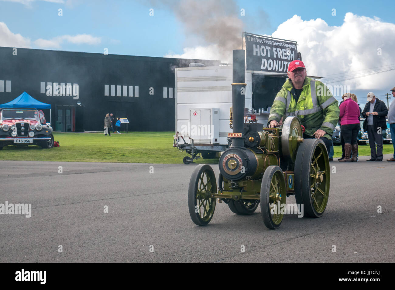 Uomo alla guida di modello in miniatura con trazione a vapore motore, Ruote e ali evento 2016, East Fortune, East Lothian, Scozia, con ciambella calda stand Foto Stock