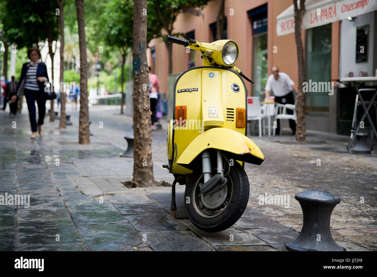 Scena di strada con giallo vintage scooter Vespa, siviglia spagna Foto Stock