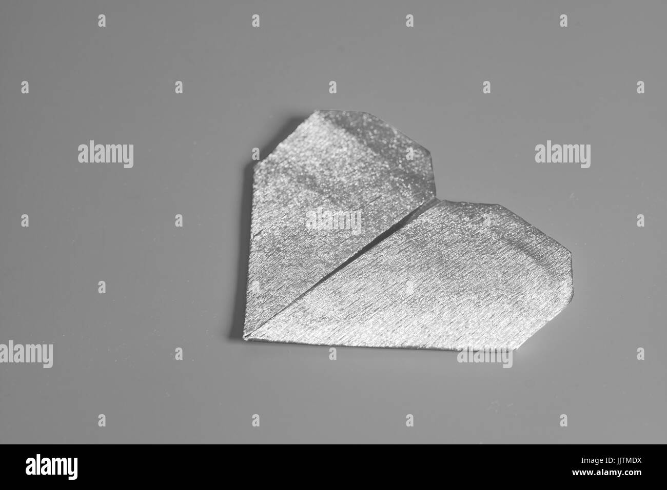 La carta il giorno di San Valentino cuore origami su sfondo grigio. Foto Stock