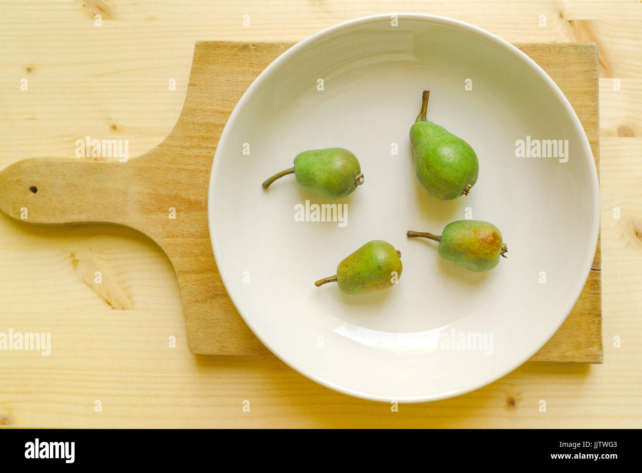 Le pere sulla piastra, frutta verde sul tavolo Foto Stock
