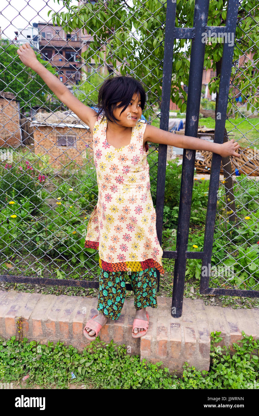 A piena lunghezza Ritratto di una giovane ragazza nepalese in piedi contro una catena collegamento recinto. Foto Stock