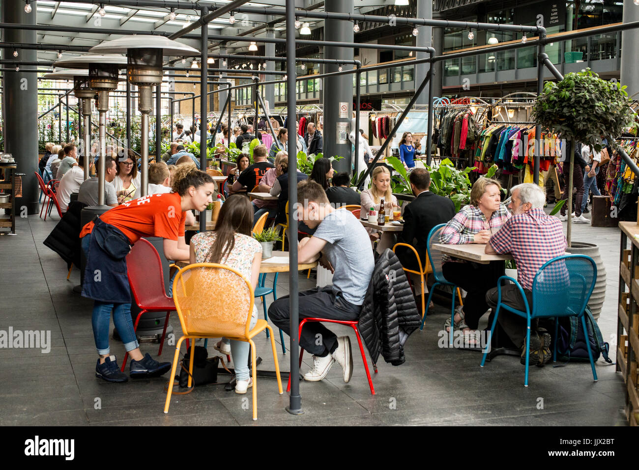 Persone mangiare nella zona salotto all'aperto di un ristorante locale in Spitalfields mercato coperto. Spitalfields, East London, Regno Unito Foto Stock