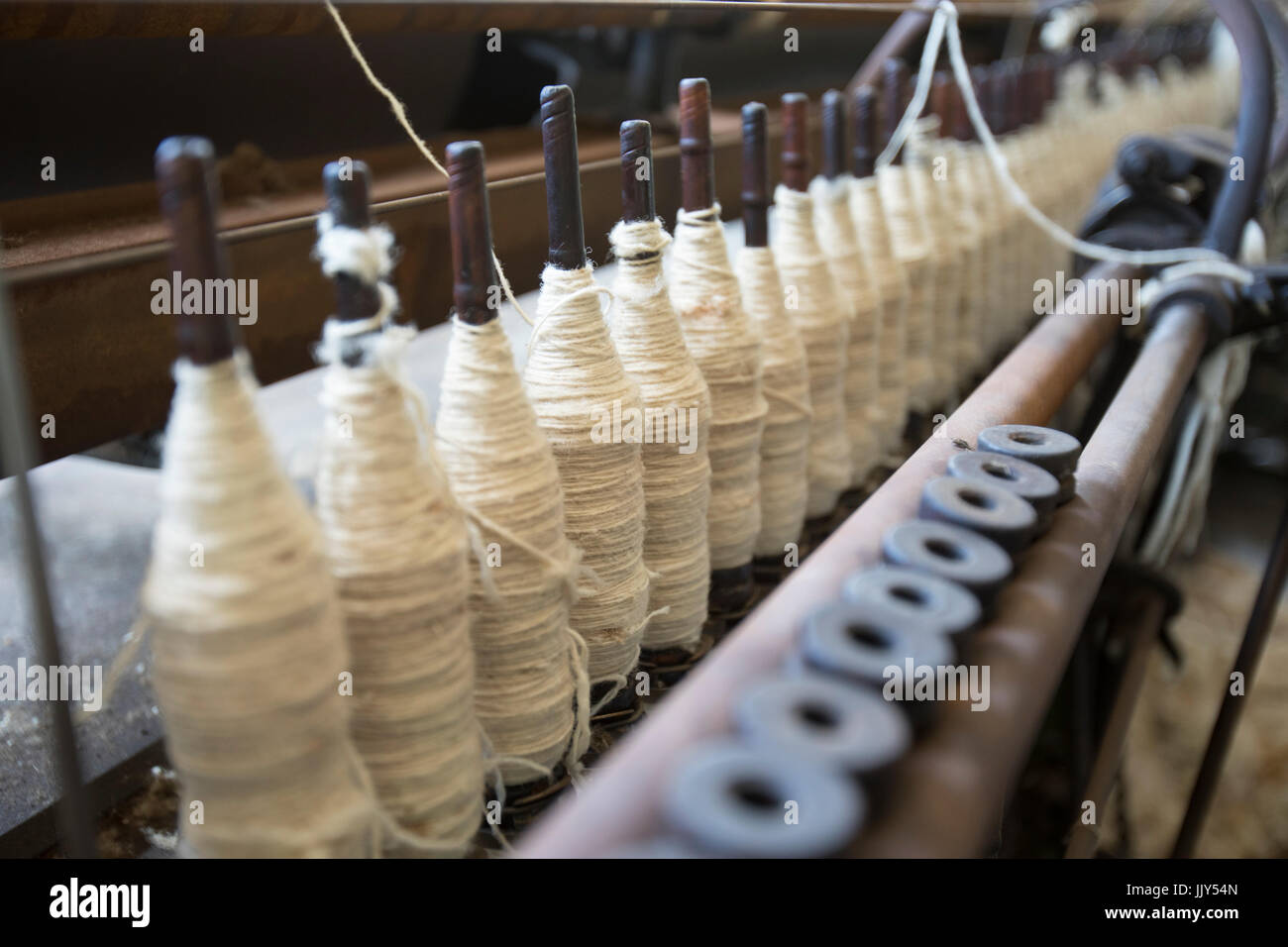 Rocchetti di lana bianca filo su bobine in legno in fabbrica vintage. Foto Stock