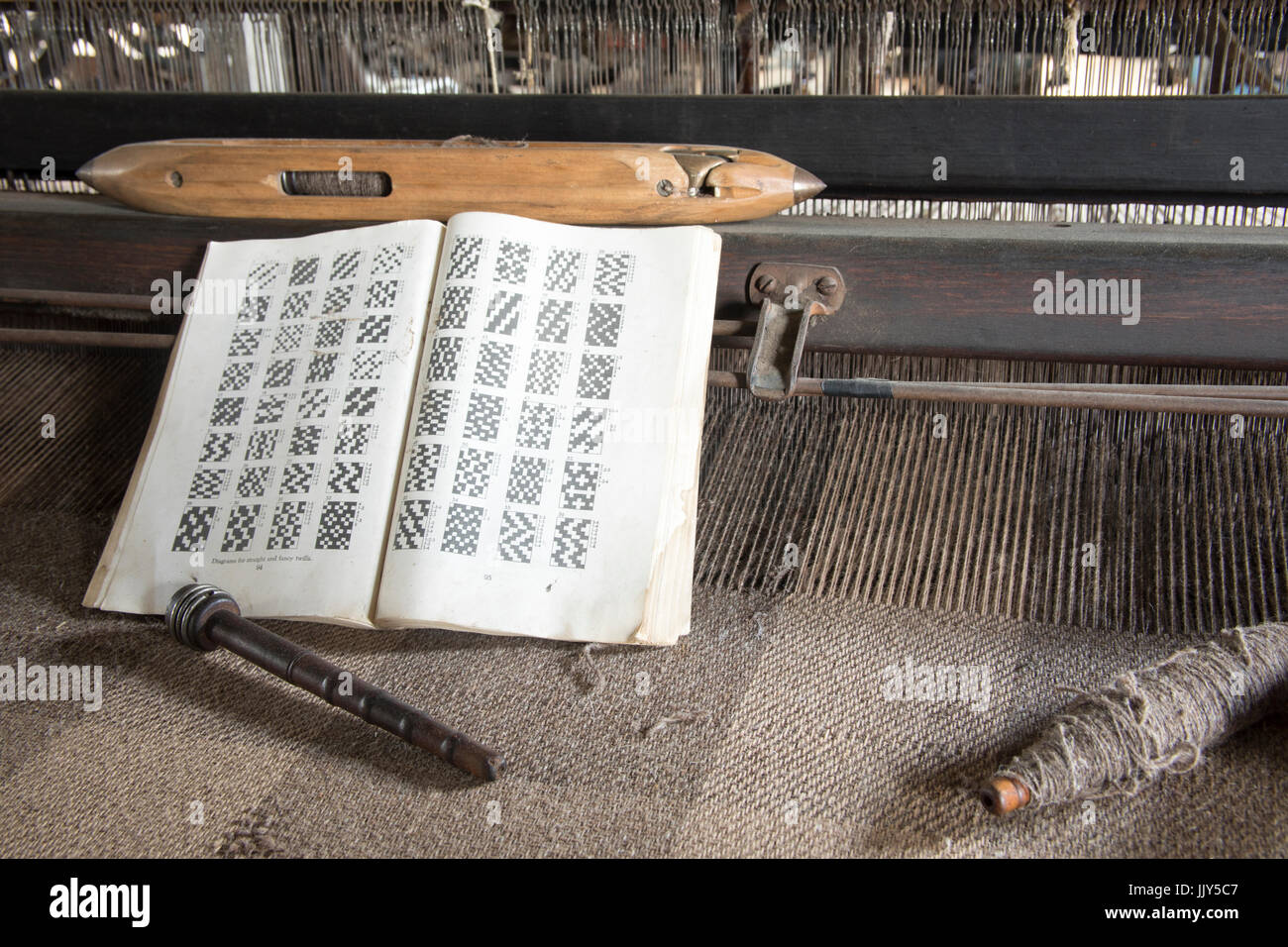 Antico mulino di lana di apparecchiature con bobina in legno e lo stelo con libro di configurazioni di tessitura. Foto Stock