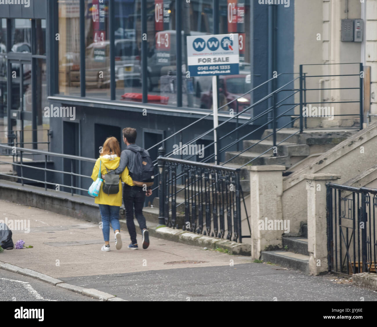 Coppia giovane camminando a braccetto con in vendita segno acquirenti per la prima volta Foto Stock