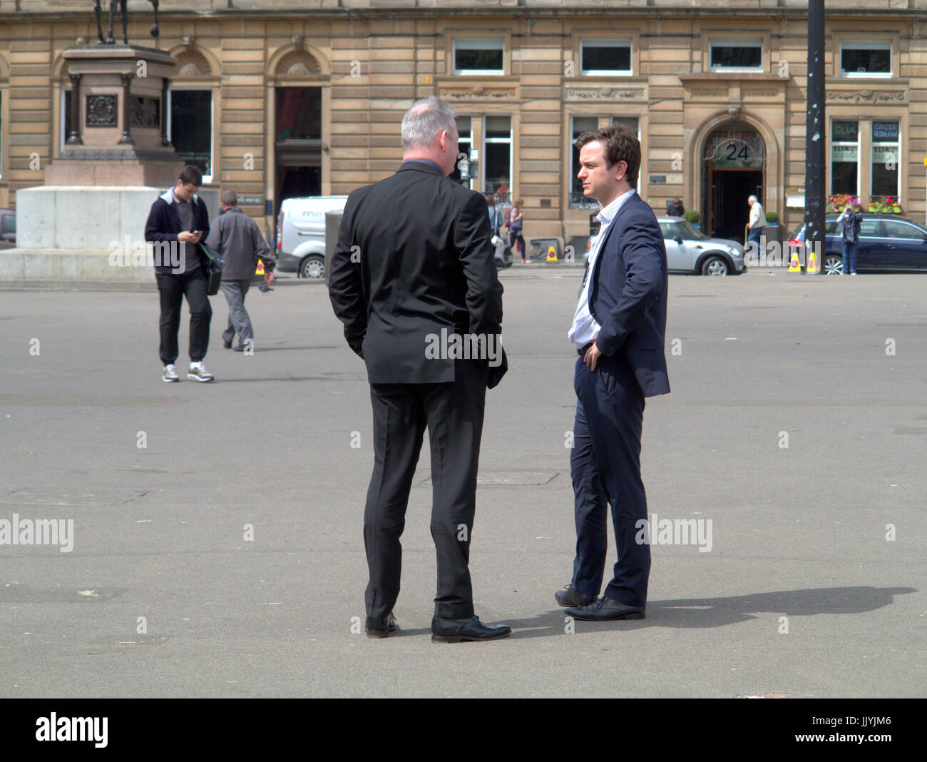 Uomini d'affari in giacca parlando sulla strada a George Square Glasgow Foto Stock