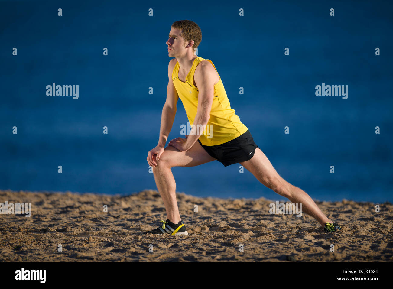 Runner riscaldare lo stiramento dei muscoli delle gambe Foto Stock