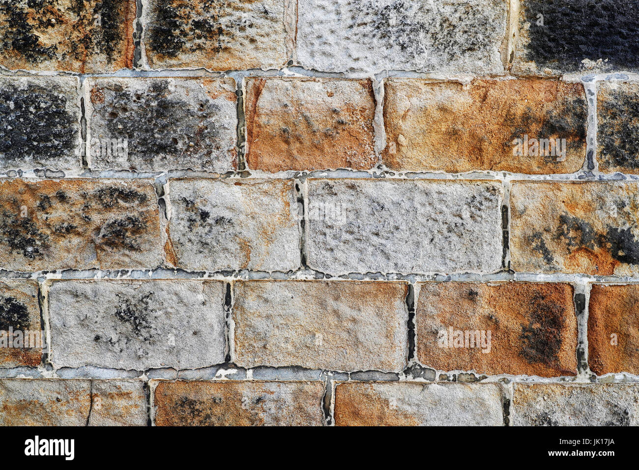 Una sezione di sabbia di un muro di pietra che mostra colore ricco e un anche la posa della pietra. Foto Stock