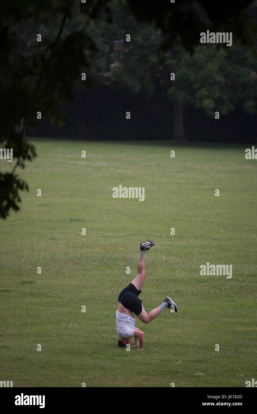 Un capovolto l uomo rimane bilanciato sulla sua testa in un parco pubblico - uno in una sequenza di quattro - il 19 luglio 2017, in Ruskin Park, South London borough di Lambeth, Inghilterra. Foto Stock