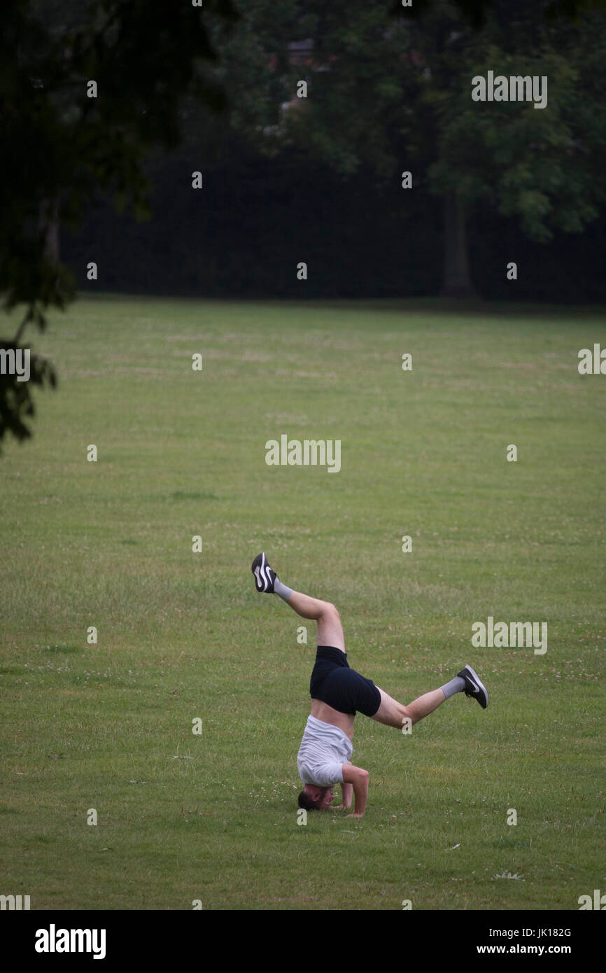 Un capovolto l uomo rimane bilanciato sulla sua testa in un parco pubblico - uno in una sequenza di quattro - il 19 luglio 2017, in Ruskin Park, South London borough di Lambeth, Inghilterra. Foto Stock