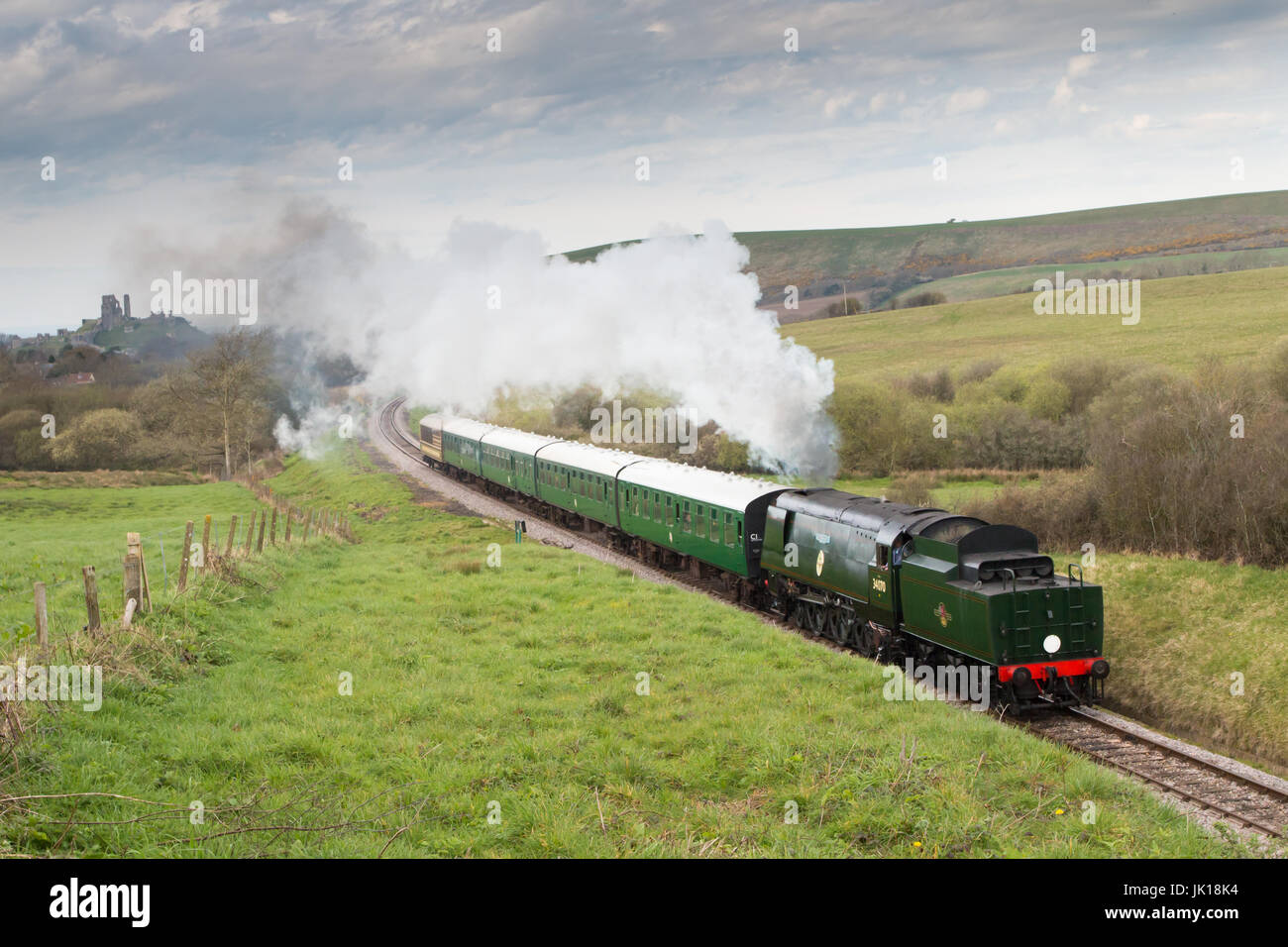 Corfe Castle: 1940s-costruito Treno a Vapore Ferrovia Meridionale Bulleid Pacific n. 34070 'Manston' mostrato in viaggio lontano da Corfe Castle in background. Foto Stock