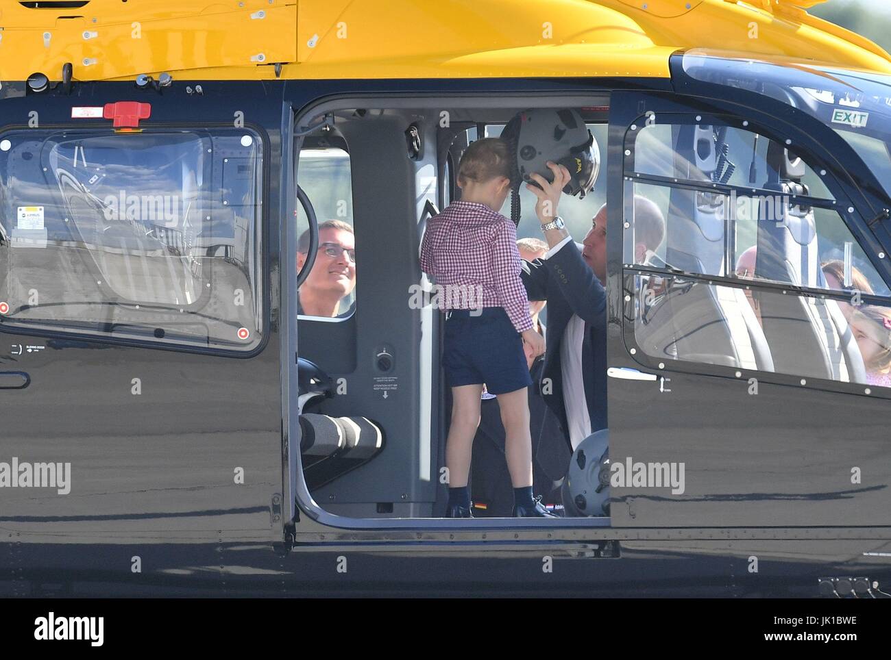 Prince George sorge in un salvataggio in elicottero come suo padre il Duca di Cambridge luoghi un casco sulla sua testa, durante una visita a Airbus ad Amburgo, in Germania con la Duchessa di Cambridge e sorella Princess Charlotte. Foto Stock