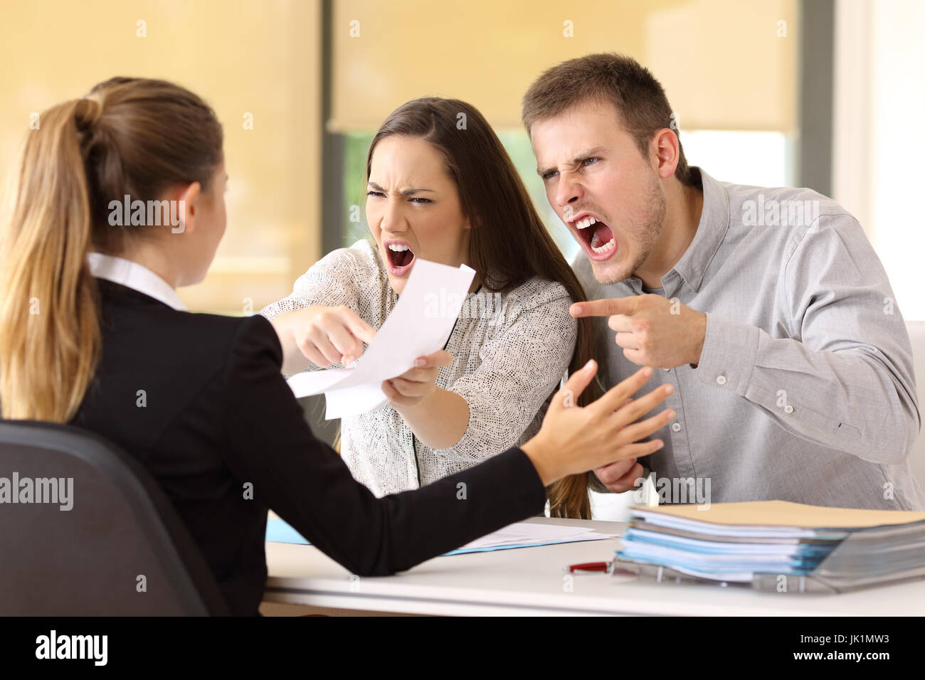 Arrabbiato giovane sostenendo e gridando ad un lavoratore di ufficio Foto Stock