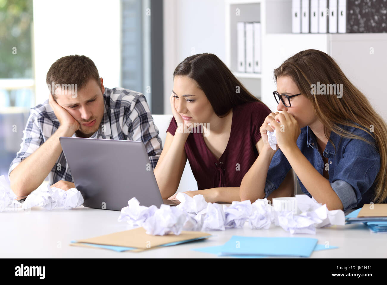 Tre frustrati gli imprenditori cercando di fare un lavoro difficile sulla linea in ufficio Foto Stock