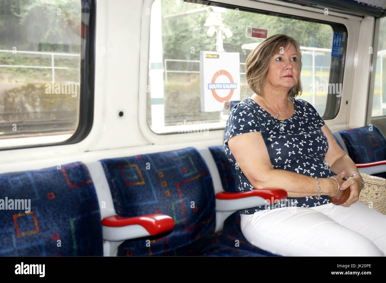 Attraente donna di mezza età che viaggiano su London city, tubo di South Ealing stazione, Inghilterra Foto Stock