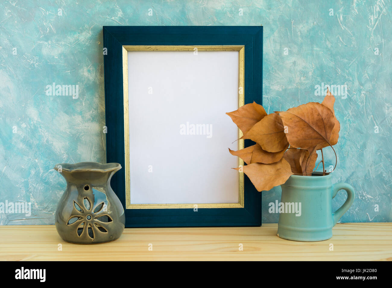 Blu e cornice dorata mockup, muro di cemento di sfondo, tavolo in legno e friggere le foglie, aroma terapia lampada, autunno, caduta, tranquillità, relax Foto Stock