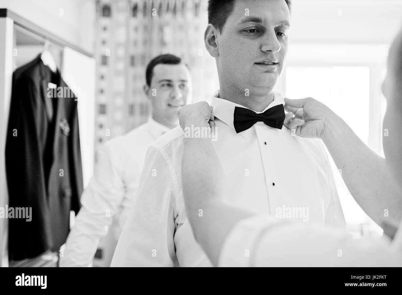 Disponibile groomsmen o bestmen aiutando lo sposo per ottenere pronto per le sue nozze. Foto in bianco e nero. Foto Stock