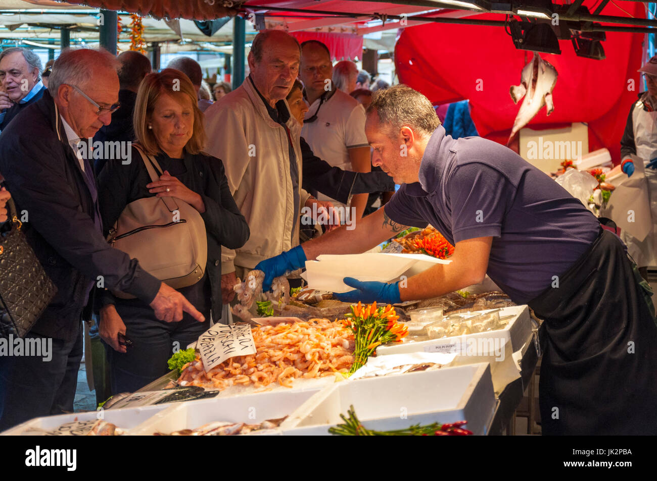 L'uomo l'acquisto di pesce in una fase di stallo in vendita al mercato di Rialto di Venezia Italia Foto Stock