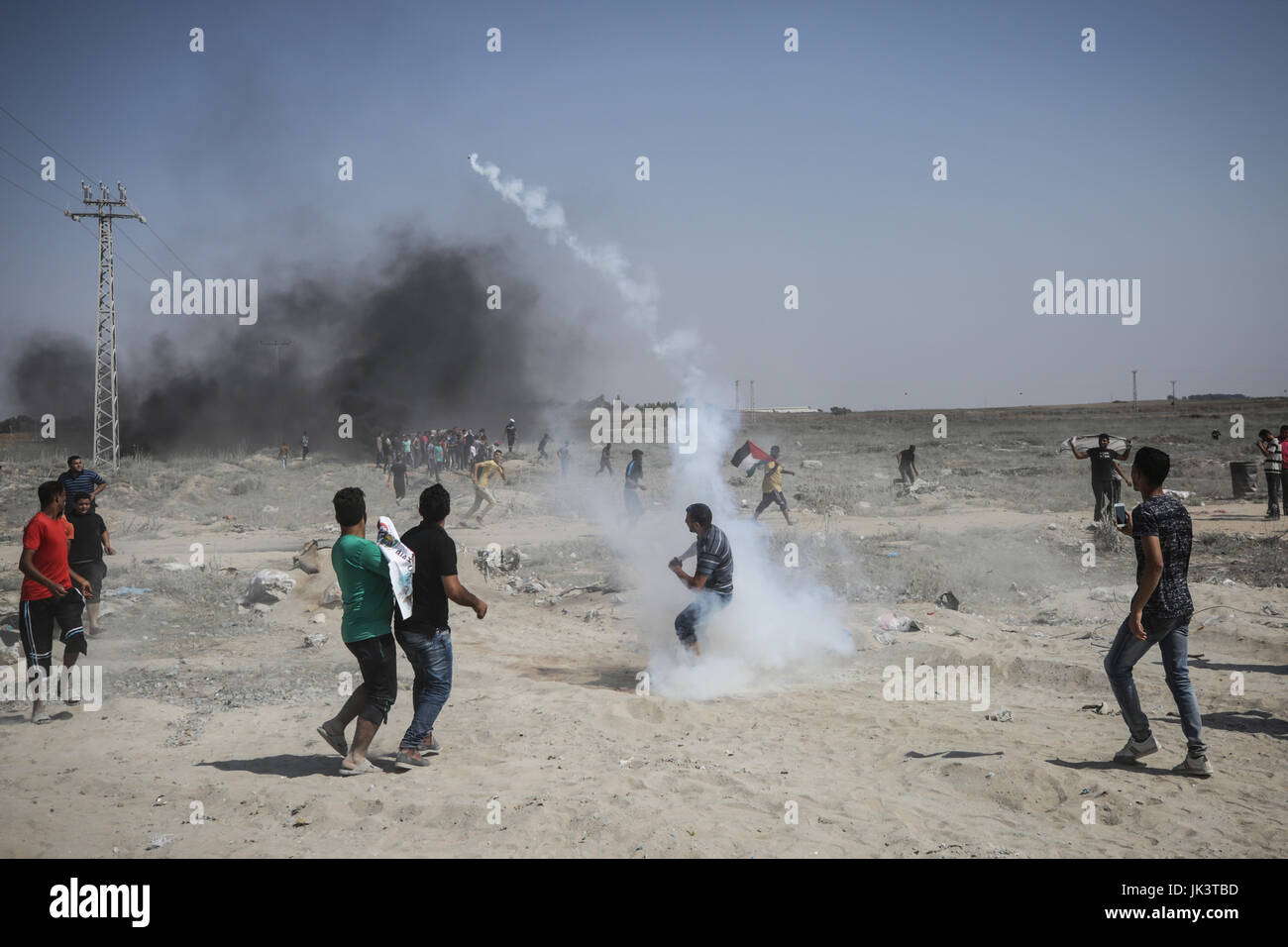 La striscia di Gaza, la striscia di Gaza. 21 Luglio, 2017. Un manifestante palestinese getta un canister gas lacrimogeno sparato dai soldati israeliani indietro durante gli scontri sul confine israeliano con la striscia di Gaza, Venerdì, 21 luglio 2017. Un escalation disputa per i rivelatori di metallo a una contestazione di Gerusalemme santuario è diventata violenta il venerdì, l'impostazione off diffusa scontri tra palestinesi pietra-tubi espulsori e truppe israeliane. Credito: Nidal Alwaheidi/Pacific Press/Alamy Live News Foto Stock