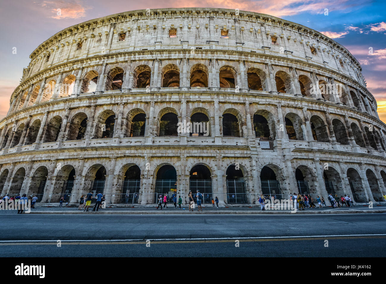 Il Colosseo di Roma in prima serata con un cielo colorato in background e turisti visite turistiche Foto Stock