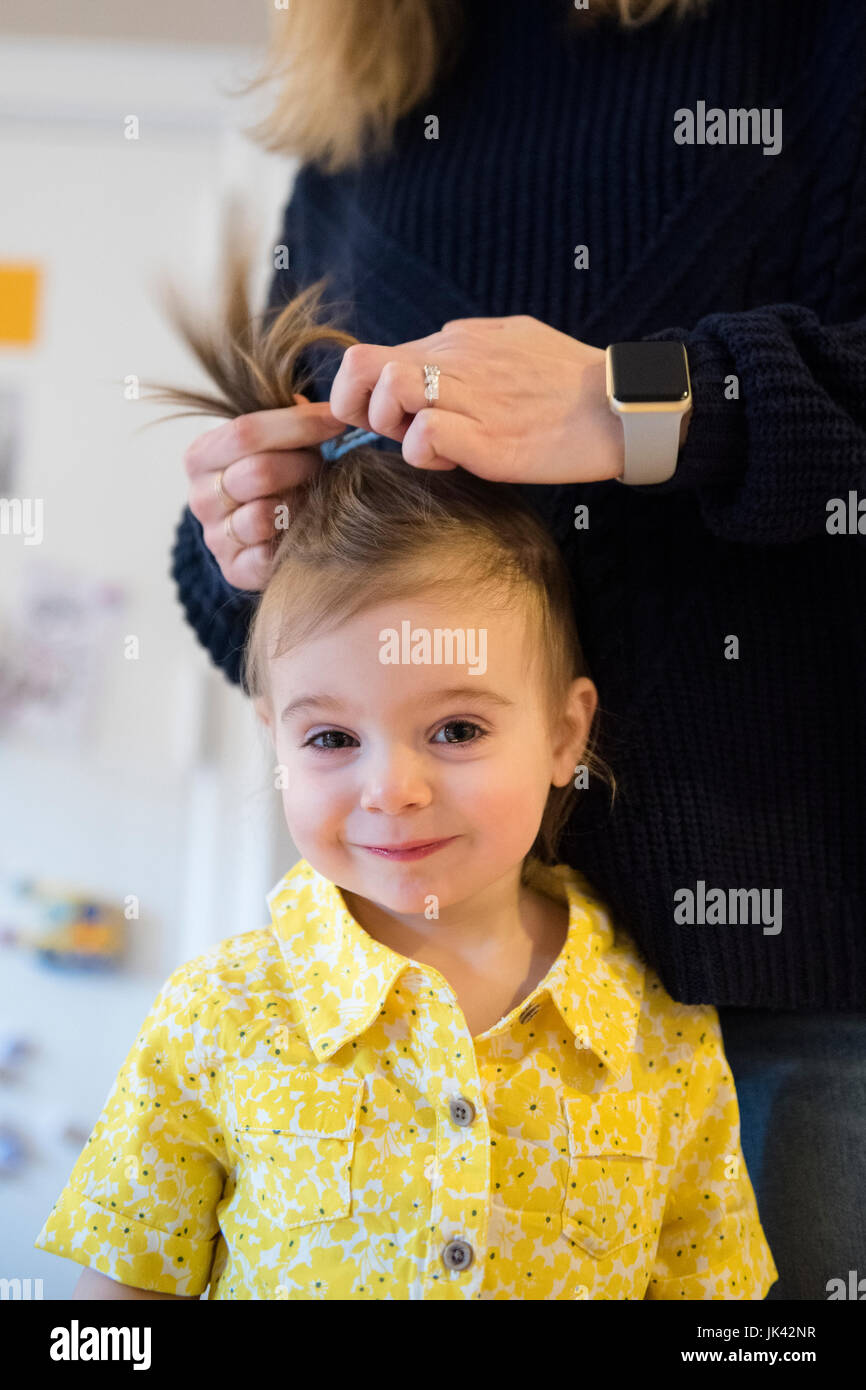 Madre caucasica per lo styling dei capelli della bimba Foto Stock