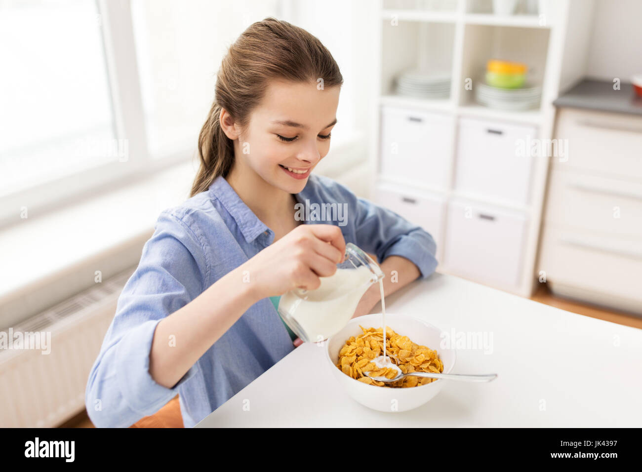 Ragazza felice di fare colazione in cucina domestica Foto Stock