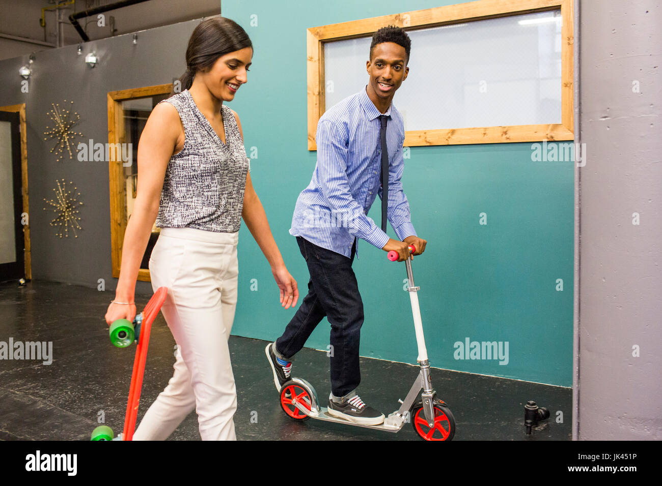 Uomo e donna con skateboard e scooter in ambienti interni Foto Stock