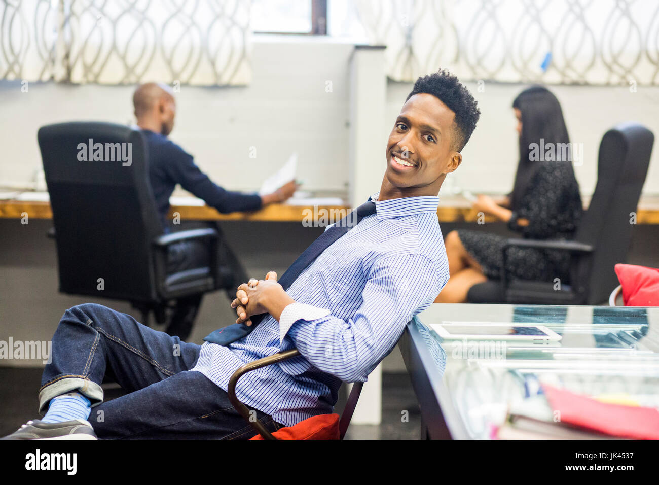 Ritratto di sorridere uomo nero rilassante in ufficio Foto Stock