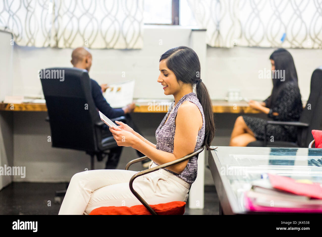 Donna asiatica con tavoletta digitale in ufficio Foto Stock