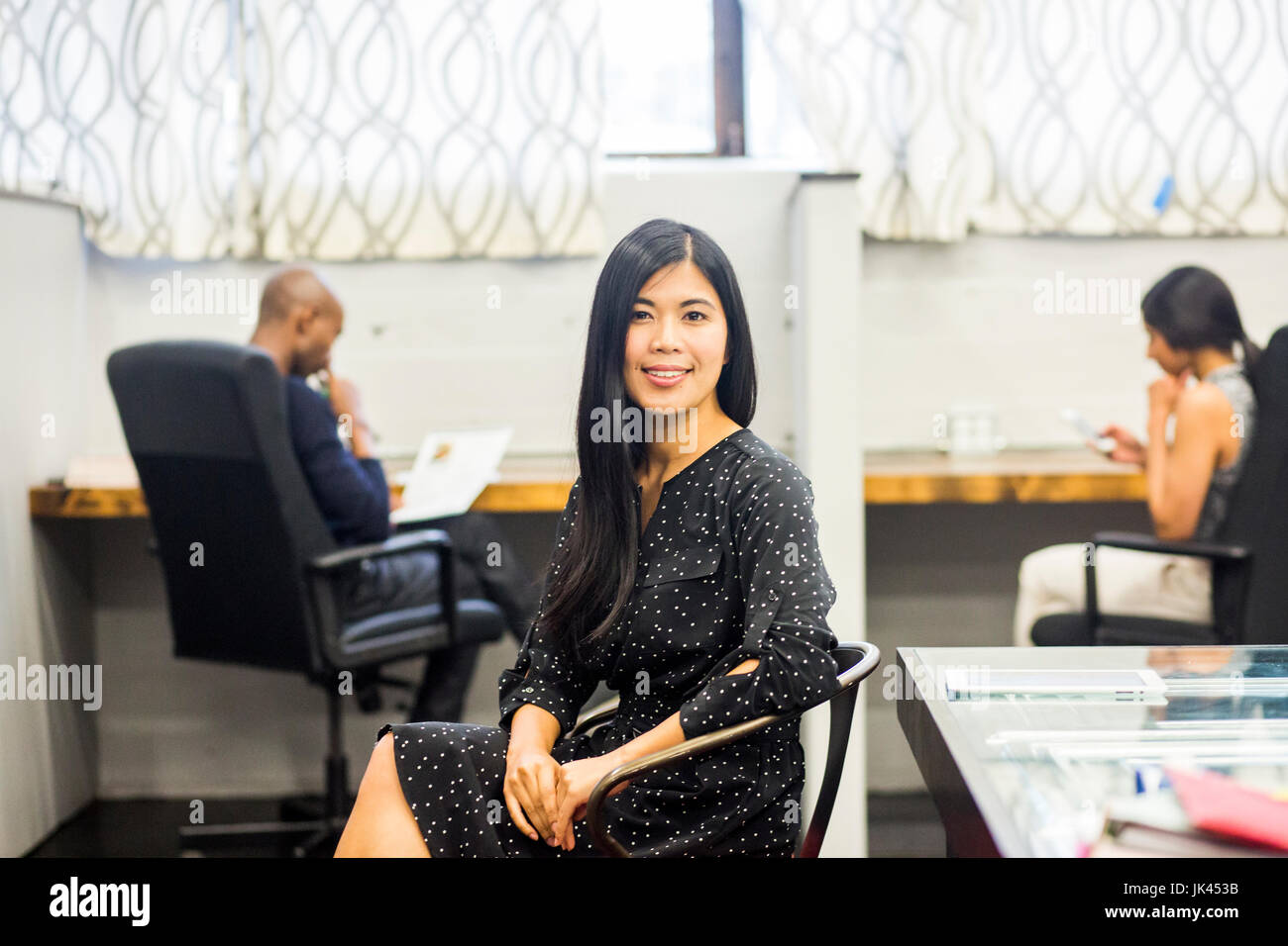 Ritratto di sorridere donna asiatica seduto in ufficio Foto Stock