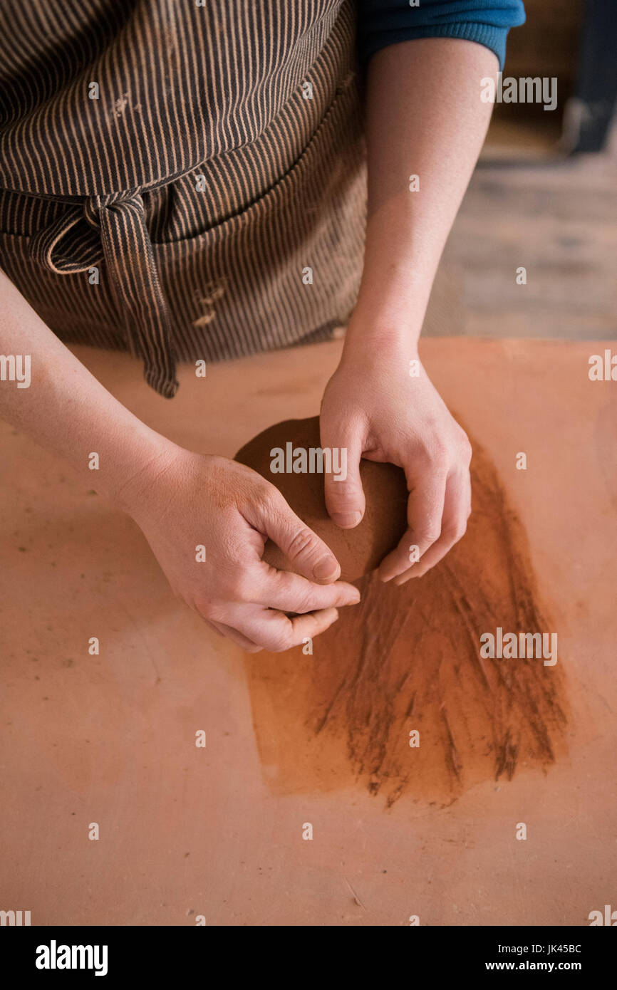 Le mani della donna caucasica laminazione di argilla in ceramica Foto Stock